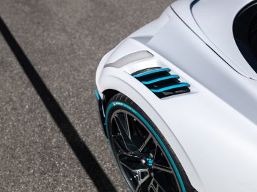 Close-up van het achterspatbord en het stuur van een witte Bugatti Divo, met zwarte velgen en turquoise accenten.
