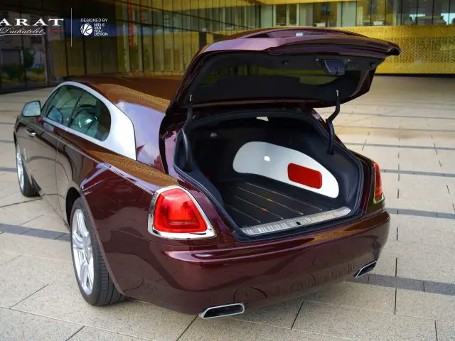 Open kofferbak van een Rolls-Royce Silver Spectre Shooting Brake met ruime kofferbak met wit interieur, geparkeerd in een stedelijke omgeving.
