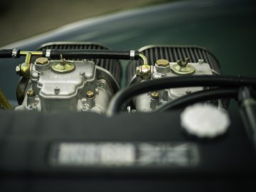 Close-up van de motor van een Caterham Super Seven 1600 met gedetailleerde carburateurs en metalen onderdelen.