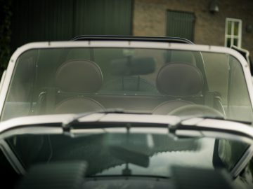 Kijk door de voorruit van een Caterham Super Seven 1600 cabriolet, met de voorstoelen en de achteruitkijkspiegel.