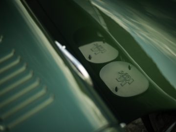 Close-up van een groene Caterham Super Seven 1600's tankdop met klassieke "niet-roken" en "ontvlambare" symbolen.