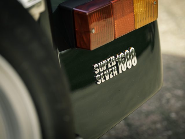 Close-up van het achterste deel van een groene auto met het achterlicht en het embleem "Caterham Super Seven 1600".