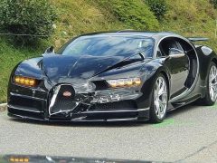 Zwarte Bugatti Chiron met schade aan de voorkant als gevolg van een ongeval, geparkeerd op een weg.