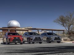 Drie Lexus-voertuigen geparkeerd langs de weg met een futuristische observatoriumkoepel op de achtergrond onder een helderblauwe lucht.