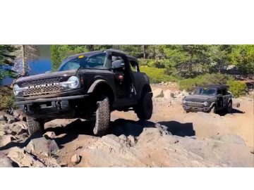 Twee Ford Bronco's off-road op een rotsachtig terrein nabij een bos.