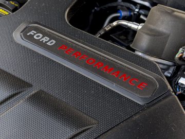 Een close-up van een Ford Focus ST-motorkap in een auto, waarbij het merklogo op een zwart gestructureerd oppervlak wordt benadrukt.