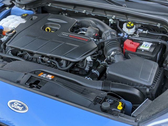 Close-up van de open motorruimte van een Ford Focus ST, met een gedetailleerd beeld van een Ecoboost-motor en verschillende componenten.