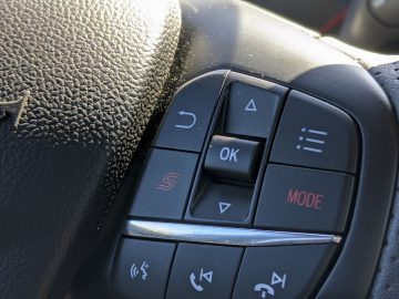 Close-up van de Ford Focus ST-stuurwielbedieningen, inclusief knoppen voor gespreksafhandeling, spraakopdrachten en media-instellingen.