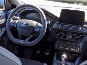 Binnenaanzicht van een Ford Focus ST met het stuur, het dashboard, de versnellingspook en het infotainmentsysteem.