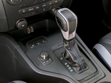 Automatische versnellingspook in een Ford Ranger met omringende bedieningselementen en indicatoren, gemarkeerd door binnenverlichting.