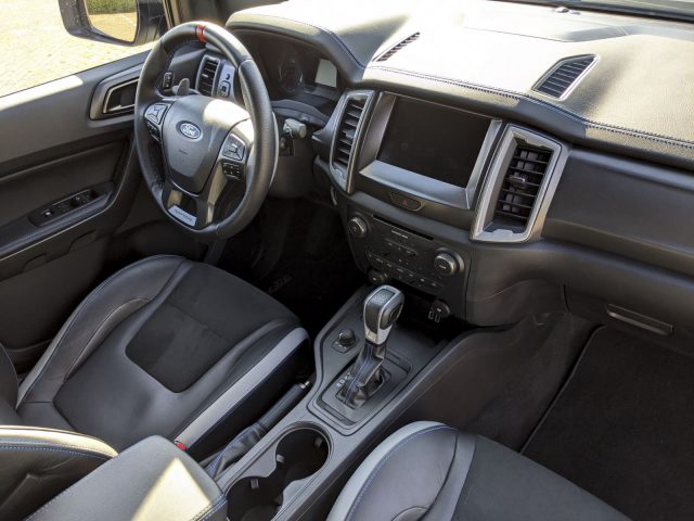 Binnenaanzicht van een Ford Ranger met lederen stoelen, voorzien van een stuur met bedieningselementen, versnellingspook en dashboard met touchscreen.