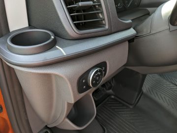 Interieur van een Ford Transit Custom met de passagierszijde met een bekerhouder, ventilatieopening en vergrendelknoppen op het dashboard.