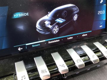 Het touchscreen-display van een Peugeot 508 HYbrid toont de status van de hybride motor met temperatuur- en AC-instellingen naast fysieke knoppen.