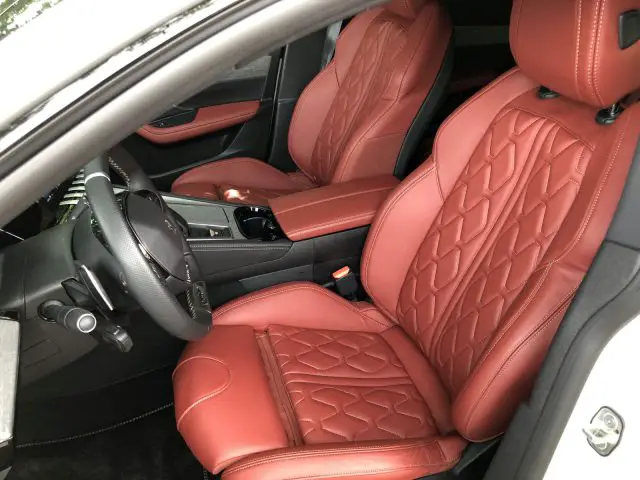 Interieur van een Peugeot 508 HYbrid met luxe roodleren stoelen met gewatteerd ontwerp, gezien vanaf de passagierszijde.