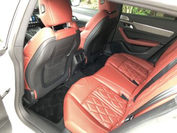 Interieur van een Peugeot 508 HYbrid met luxe roodleren stoelen met diamantstiksel, open deuren en zwarte en chromen details.