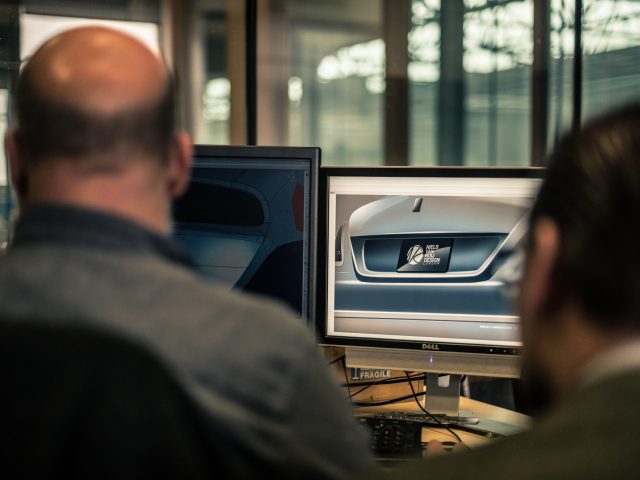 Twee professionals onderzoeken het ontwerp van een Rolls-Royce Silver Spectre Shooting Brake-deur op een computermonitor in een kantooromgeving.