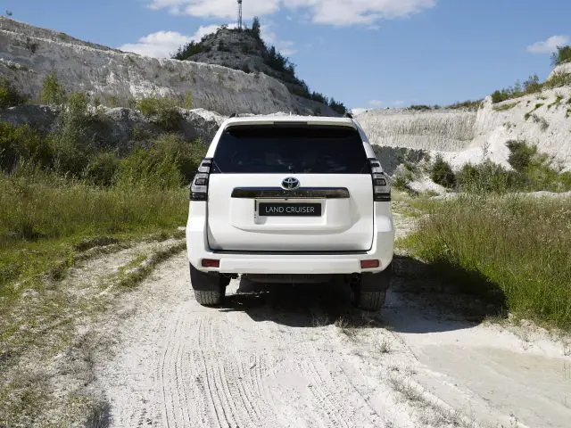 Een witte Toyota Land Cruiser geparkeerd op een stoffig pad met krijtachtige heuvels op de achtergrond.
