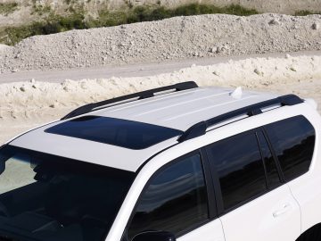 Toyota Land Cruiser geparkeerd op een grindterrein met een panoramisch schuifdak en een kalksteengroeve op de achtergrond.