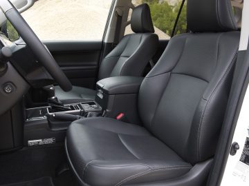 Binnenaanzicht van een Toyota Land Cruiser met leren stoelen voor bestuurder en passagier, middenconsole en dashboard in modern design.