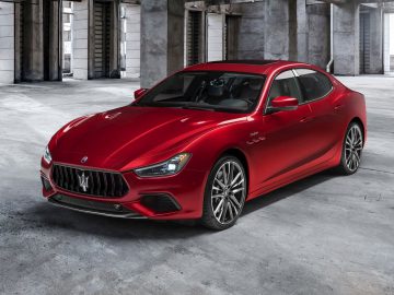 Rode Maserati Ghibli sportsedan geparkeerd in een ruime industriële garage.