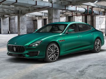 Een groene Maserati Ghibli geparkeerd in een betonnen industriële garage.
