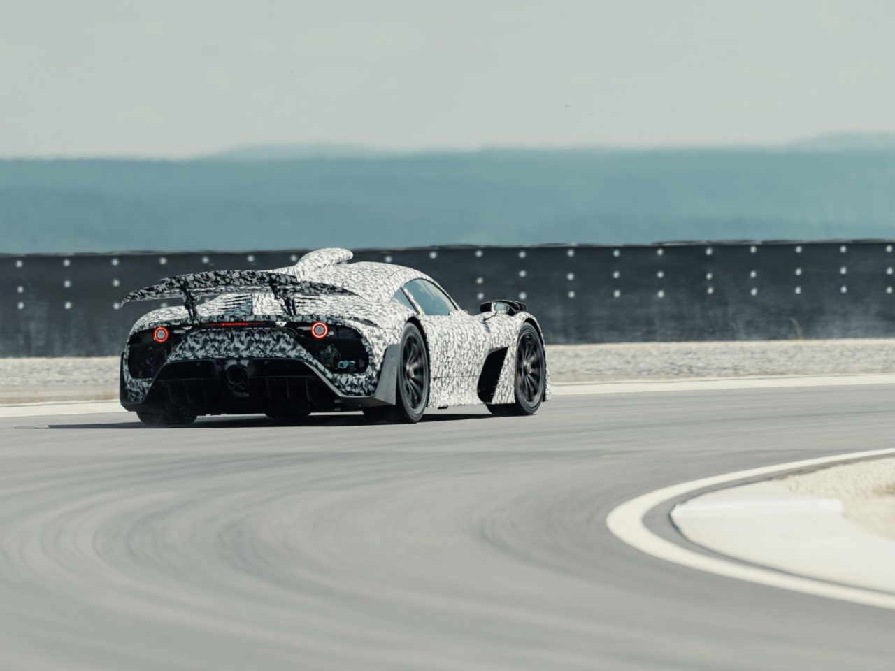 Een Mercedes-AMG Project ONE-sportwagen snelt op een racecircuit met een onscherpe achtergrond die hoge snelheid aangeeft.