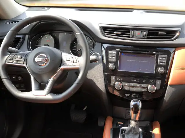 Binnenaanzicht van een Nissan X-Trail met het stuur, het dashboard en de middenconsole met multimediasysteem.