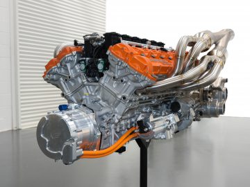 Een krachtige Gordon Murray Automotive T.50-motor met oranje en zilveren componenten tentoongesteld in een schone werkplaatsomgeving.