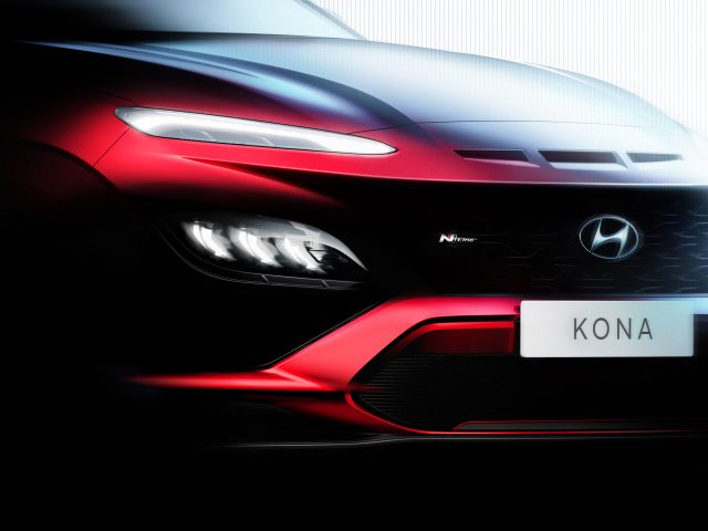 Close-up van het vooraanzicht van een rode Hyundai Kona-auto, met de grille, koplampen en een zichtbare kentekenplaat met het opschrift
