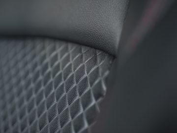 Close-up van een Toyota Yaris-autostoeltje met zwart gestructureerd leer en een diamantsteekpatroon.