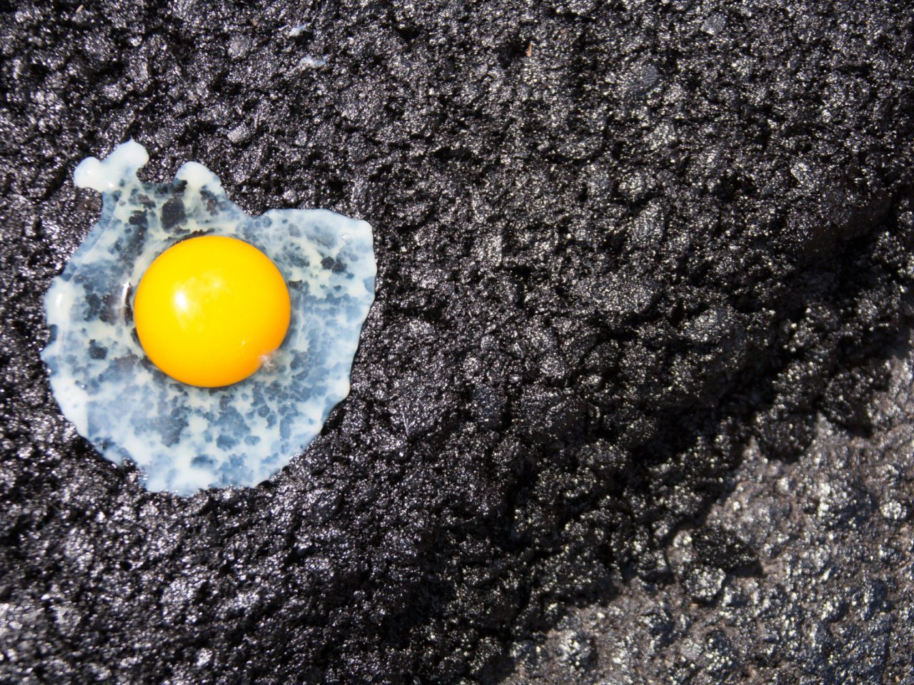 Een ei met de zonnige kant naar boven op een donkere, getextureerde winterband, waarbij de felgele dooier en het doorschijnende eiwit worden benadrukt.