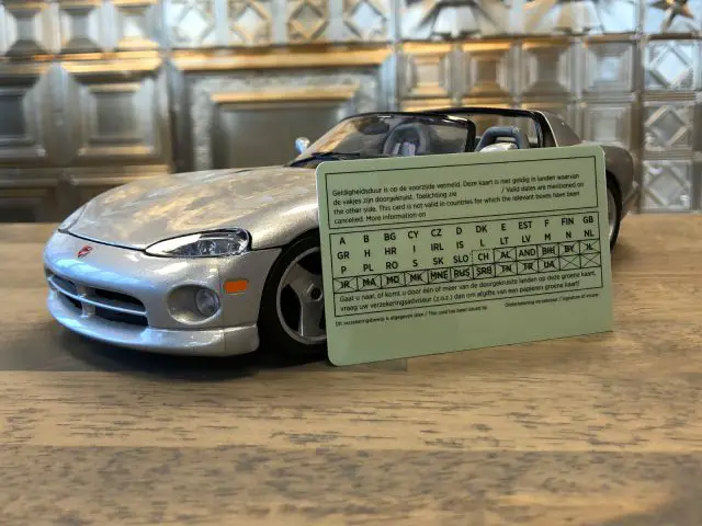 Een kleine speelgoedcabriolet voor een periodiek systeem met metalen achtergrondtegels en een Groene kaart.