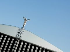 Close-up van het nieuwe Rolls-Royce-embleem, de geest van extase, tegen een helderblauwe lucht.