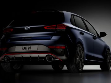 Achteraanzicht van een blauwe Hyundai i30 N tegen een donkere achtergrond, waarbij het sportieve design en de achterlichten worden benadrukt.