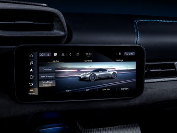 Het infotainmentscherm van de auto met verschillende voertuiginstellingen en een dynamische afbeelding van een Maserati MC20 op een circuit.