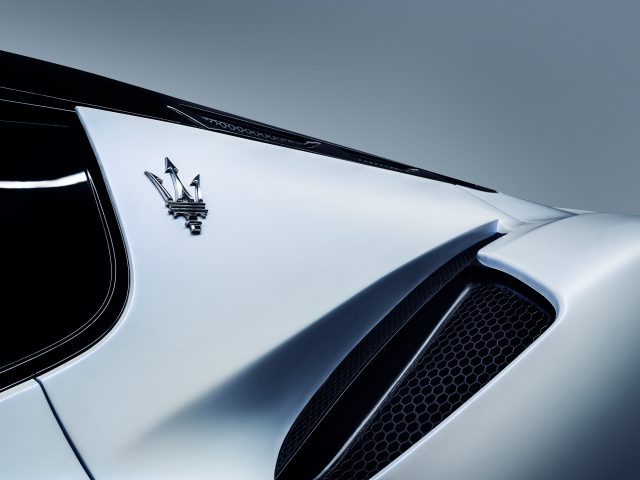 Close-up van de achterkant van een witte Maserati MC20-sportwagen met opvallend merklogo en ventilatieopeningen.