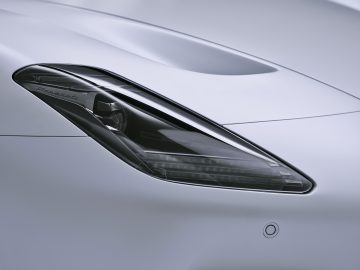 Close-up van een strakke autokoplamp met gedetailleerd ontwerp, waarin de merknaam "Maserati MC20" is gegraveerd.
