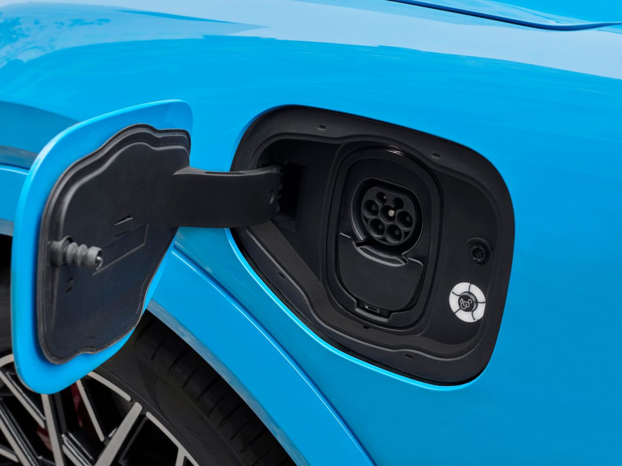 Blauwe elektrische auto met open laadpoort en een aangesloten BPM-laadkabel.