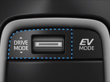 Close-up van het dashboard van een Suzuki Swace-voertuig met knoppen voor "drive-modus" en "ev-modus" met een blauw verlichte omtrek.