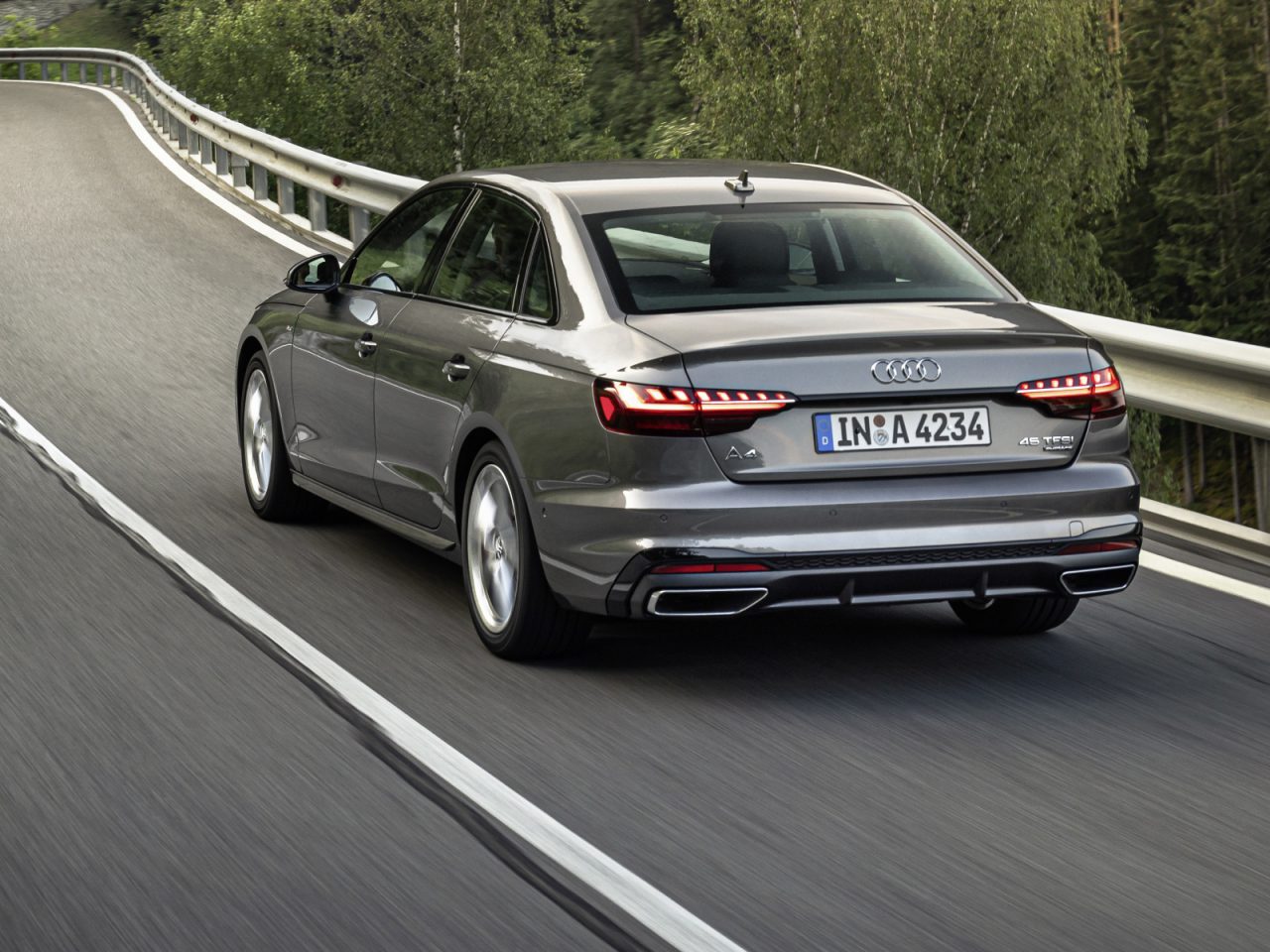 Audi A4 rijdt op een bochtige bosweg, van achteren gezien.