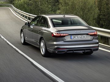 Audi A4 rijdt op een bochtige bosweg, van achteren gezien.
