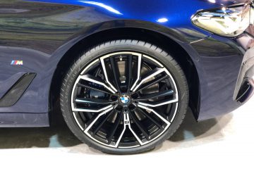 Close-up van een lichtmetalen velg van een BMW 5 Serie met blauwe en zwarte details.