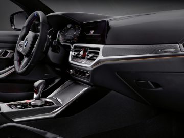 Binnenaanzicht van een BMW M3 Sedan met het stuur, het dashboard en de middenconsole met multimediabediening.