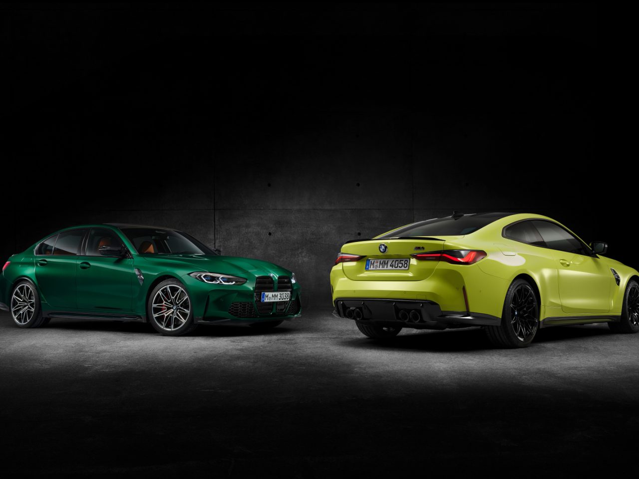 Twee BMW M3 Sedan-auto's, een groene en een gele, geparkeerd in een slecht verlichte kamer, in tegengestelde richting gericht.
