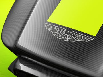 Close-up van het koolstofvezeldetail op een Aston Martin-racesimulator met het logo zichtbaar, tegen een limoengroene achtergrond.