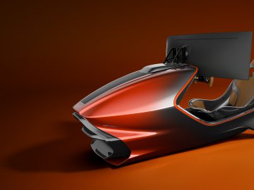 Een moderne, strakke Aston Martin-racesimulatoropstelling met een rood en zwart chassis, voorzien van een gemonteerd scherm en een geïntegreerde kuipstoel, op een oranje achtergrond.