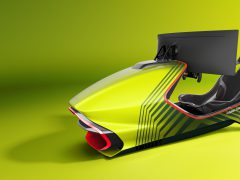 Een futuristische Aston Martin-racesimulatoropstelling met een zwarte stoel en stuur, weergegeven tegen een groene achtergrond.
