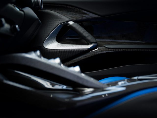 Close-up van een Ferrari Omologata-interieur, waarbij de nadruk ligt op het strakke ontwerp van de deurgreep en de zijkant van een blauw-zwart lederen stoel.