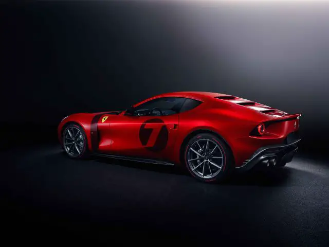 Rode Ferrari Omologata-sportwagen met nummer 7 op de deur, gezien vanaf de zijkant tegen een donkere achtergrond.