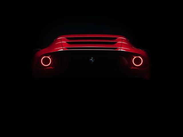 Achteraanzicht van een rode Ferrari Omologata met verlichte achterlichten en logo, tegen een donkere achtergrond.